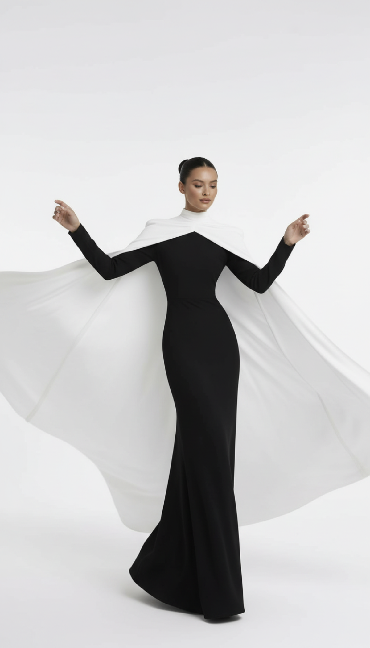 Woman wearing a black and white dress with a flowing cape on a white background