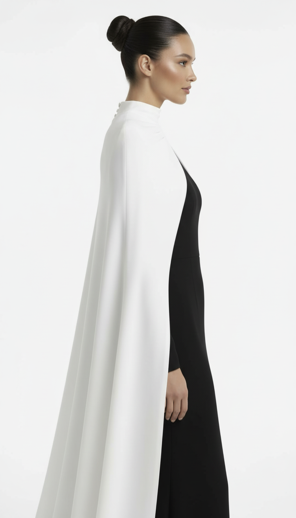 Woman wearing a long black dress with a white cape on a white background