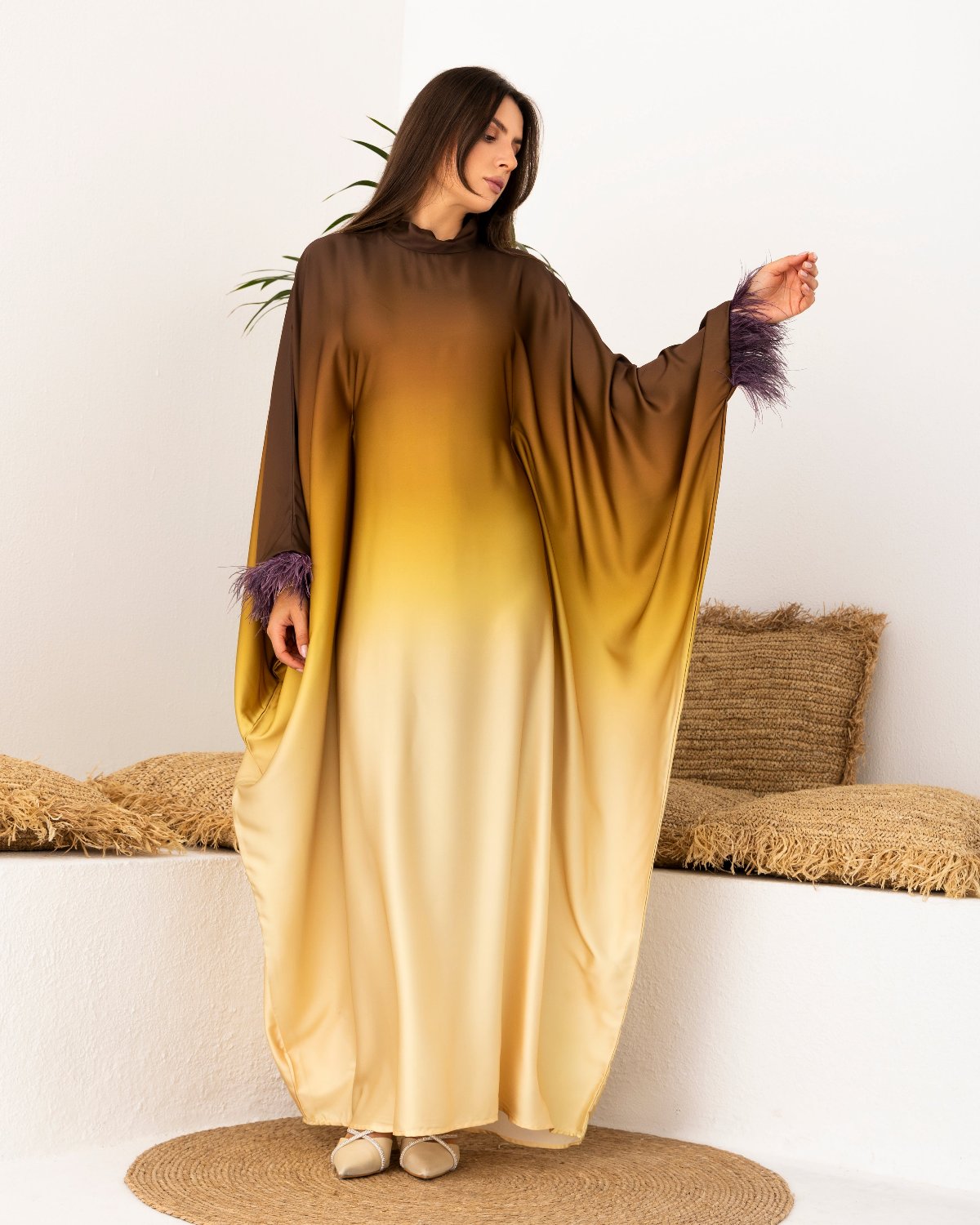 Side view of the Sahara Glow Kaftan, featuring a flowing satin design with feather details on the sleeves and an adjustable belt for a custom fit.